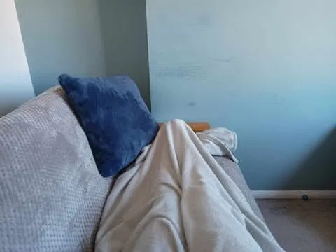 Someone putting their feet up on a futon, legs covered by a fluffy blanket