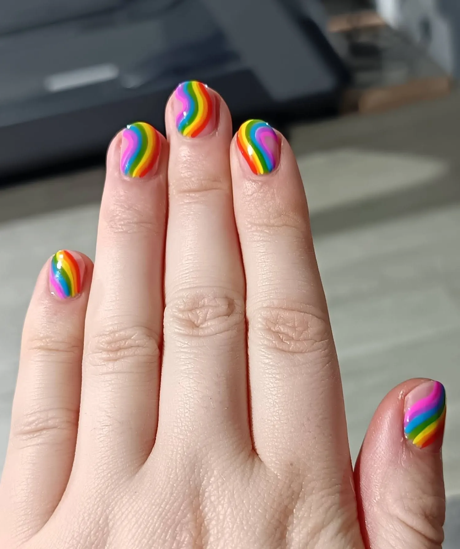 A hand with rainbow patterned nail polish